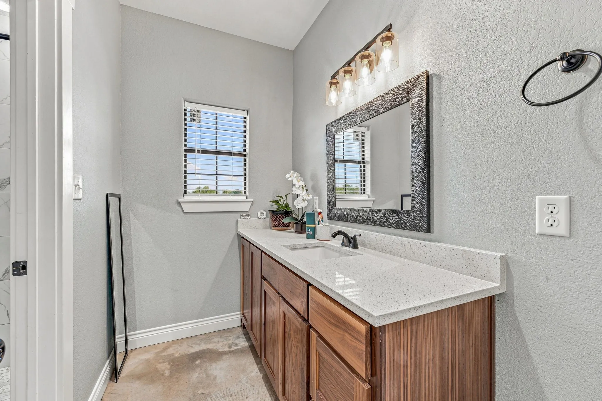 Single vanity with a light-toned countertop and wood-finish cabinetry