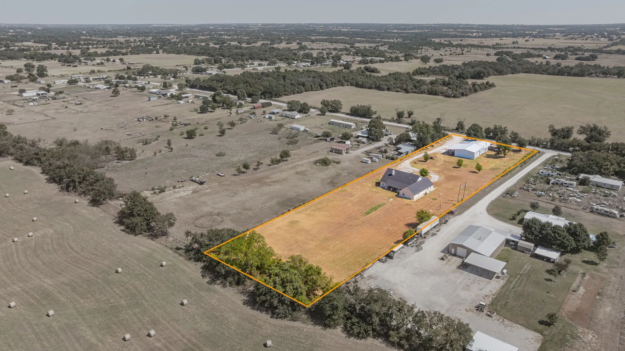 Expansive property featuring a single-story residence, multiple outbuildings, and open land