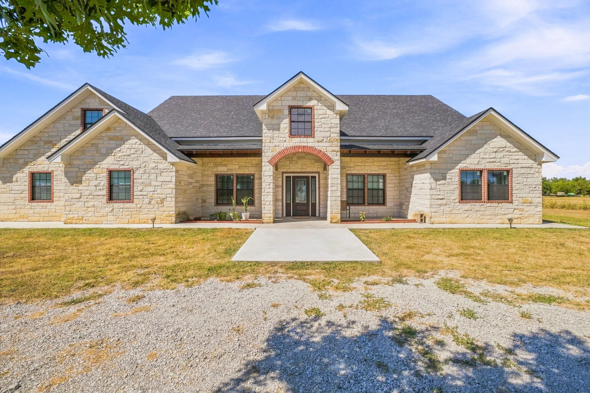 Stone exterior with dark-framed windows, a prominent gable roofline, and a concrete walkway leading to the entry