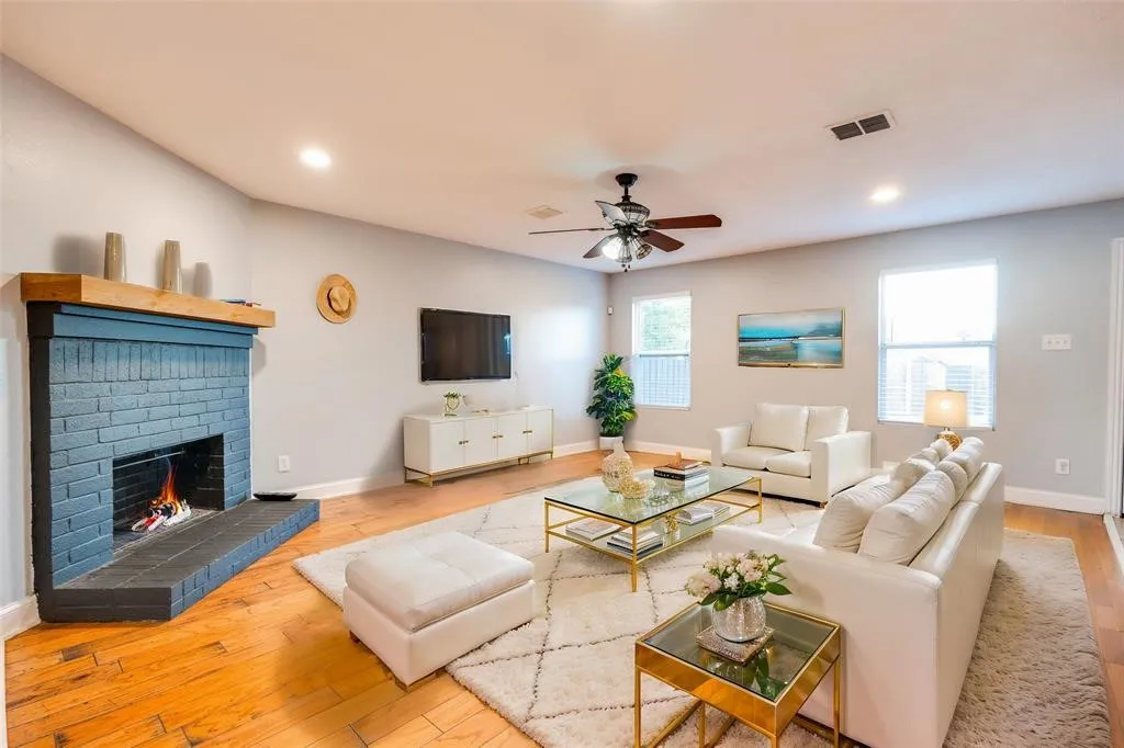 Living room featuring wood-finish flooring, a painted brick fireplace with a wood mantle, recessed lighting, and a ceiling fan