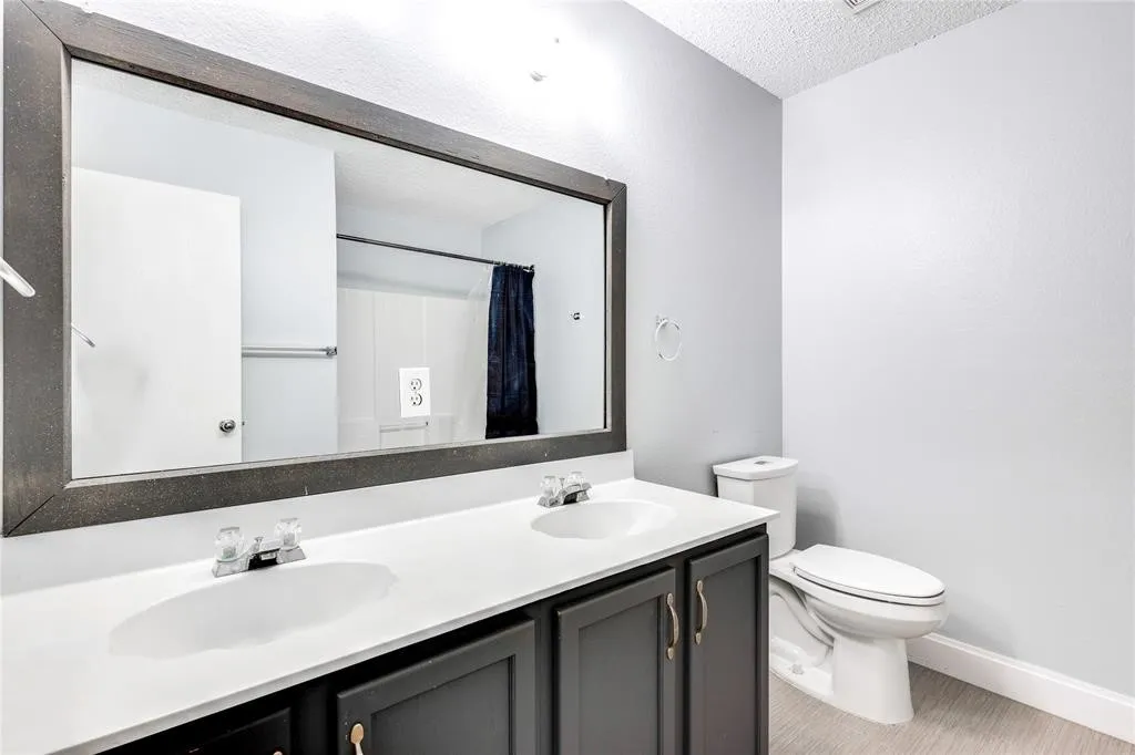 Dual vanity with integrated sinks, dark wood-finish cabinetry, and a large framed mirror
