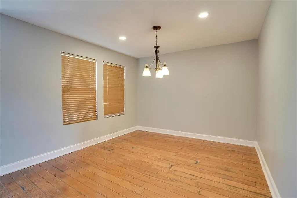 Recessed lighting, wood-finish flooring, two windows with blinds, a multi-arm chandelier, and light gray walls