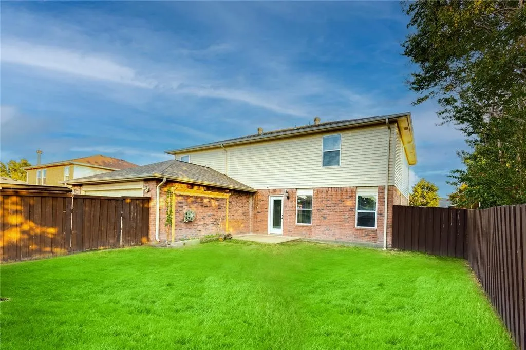 Expansive grassy yard with wood fencing, a brick and siding exterior, and a built-in patio