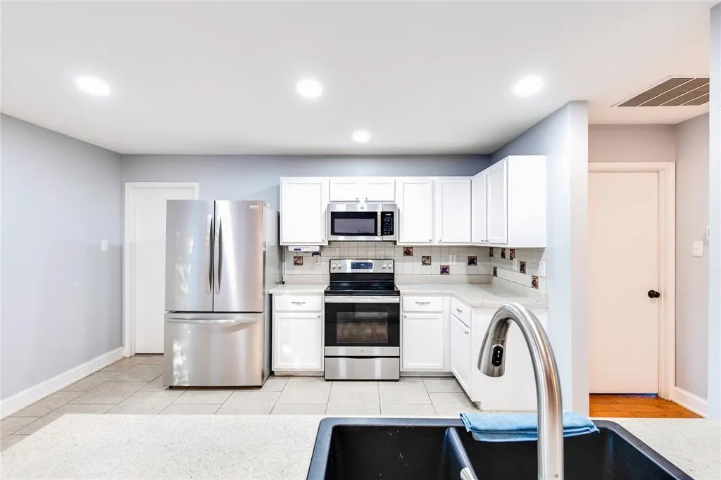 Kitchen featuring white cabinetry, stainless steel appliances, a tile backsplash, light-colored countertops, and recessed lighting