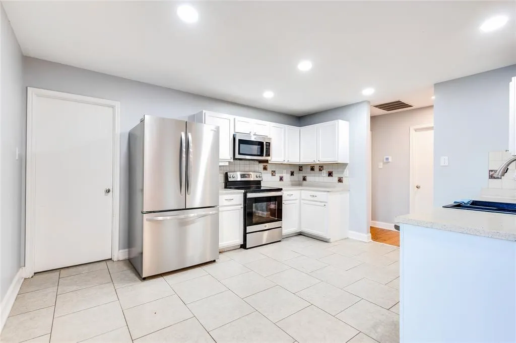 Kitchen featuring white cabinetry, light-toned tile flooring, stainless steel appliances, recessed lighting, and a tile backsplash