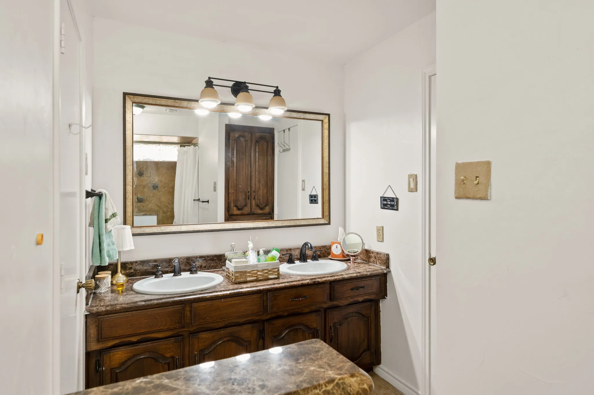 Double vanity with integrated sinks, framed mirror, and warm wood-finish cabinetry