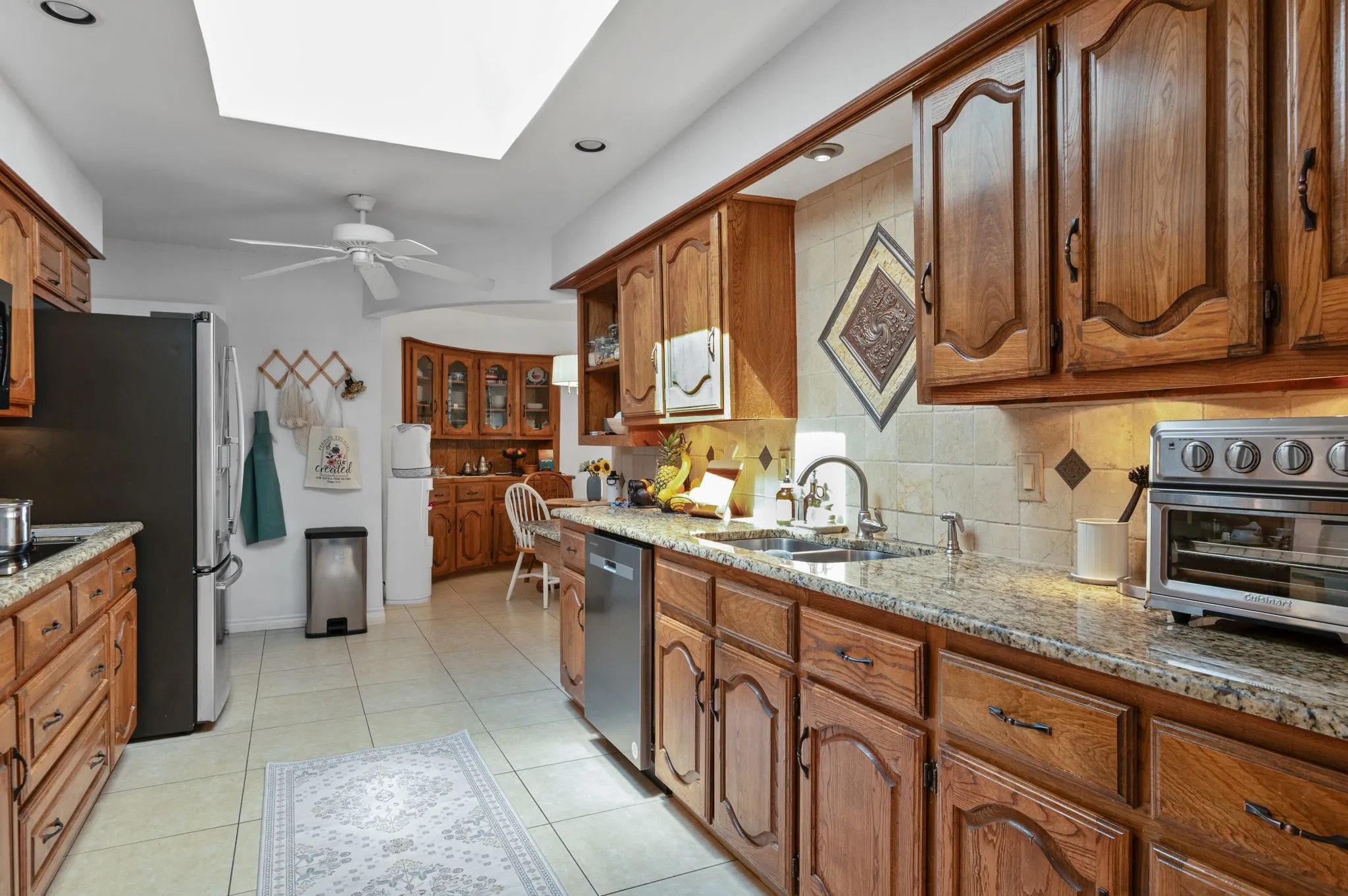 Kitchen featuring wood cabinetry, granite countertops, tile flooring, and a skylight
