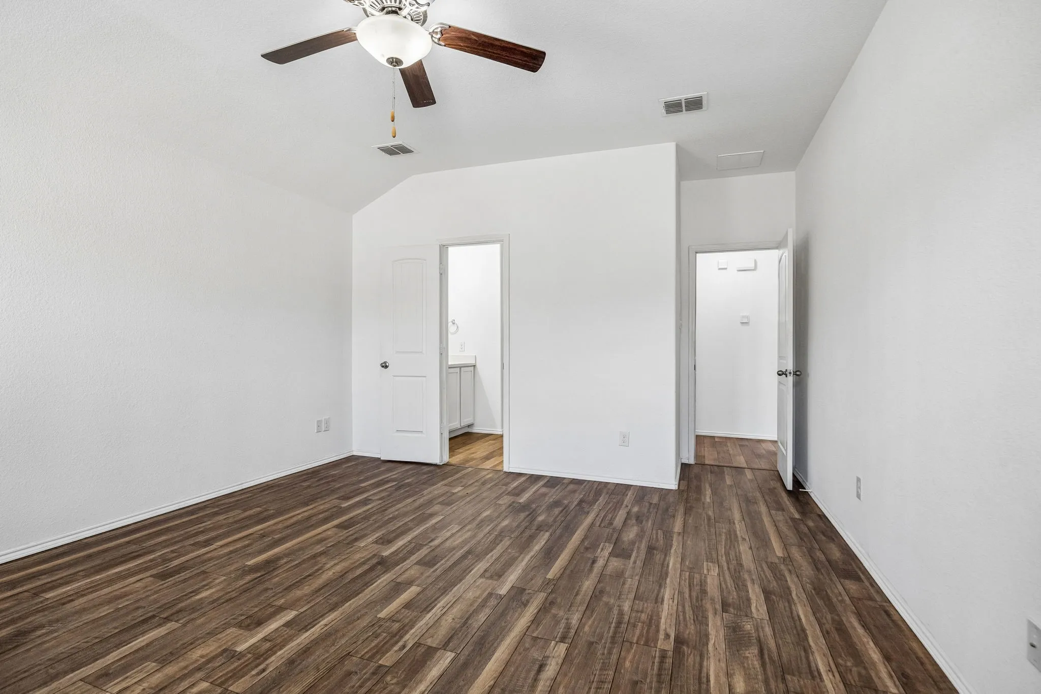 Vaulted ceiling with a ceiling fan, wood-finish flooring, and white walls