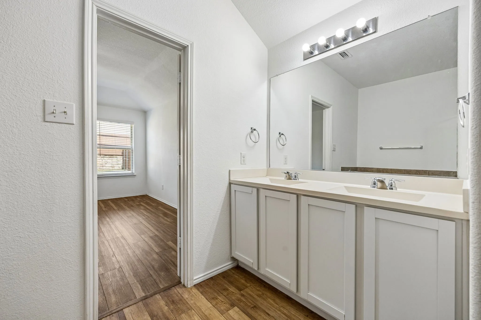 Dual vanity with white cabinetry and integrated sinks, complemented by a large wall-mounted mirror