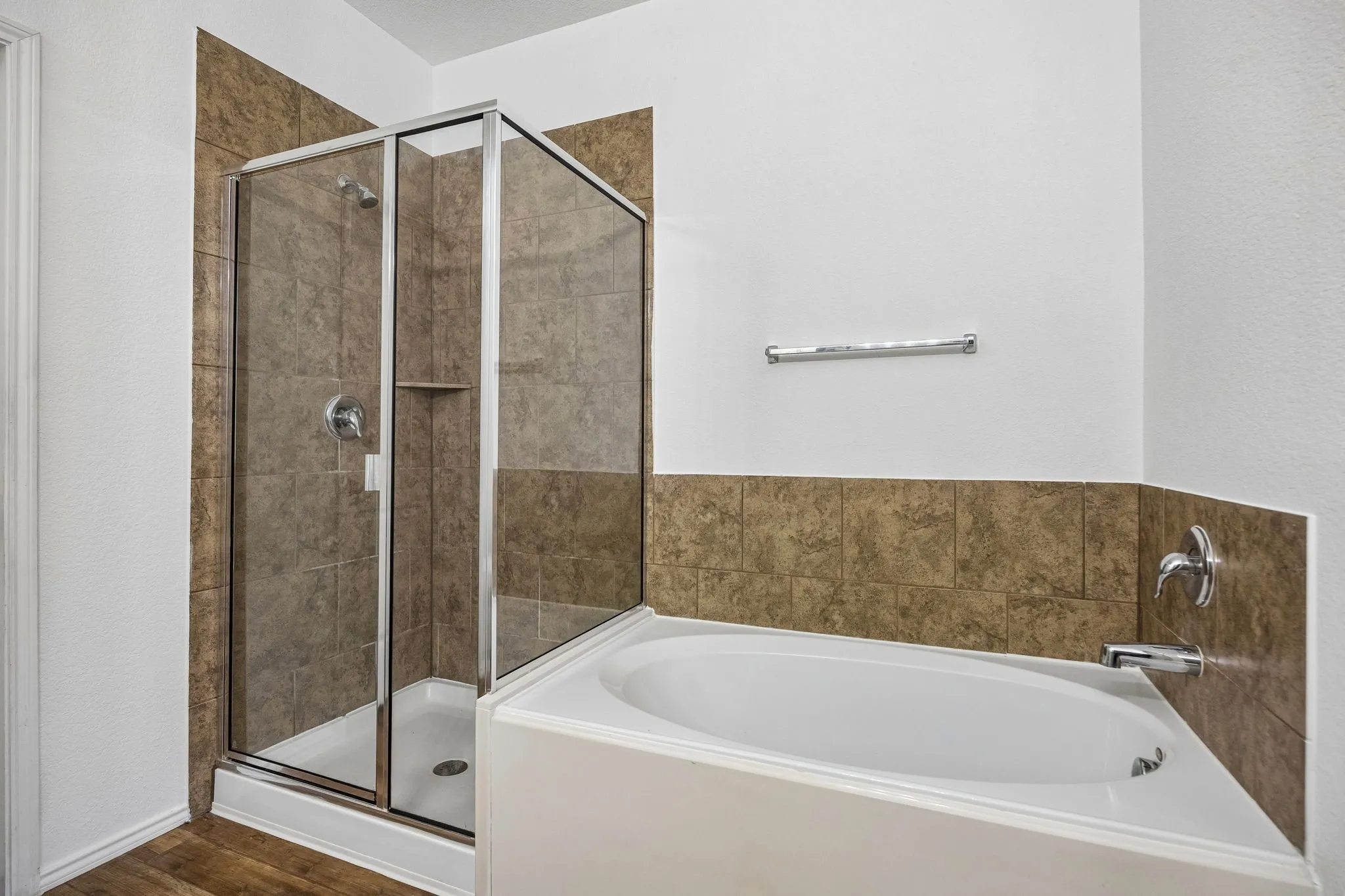 Walk-in shower with clear glass enclosure and built-in shelving, accompanied by a separate soaking tub