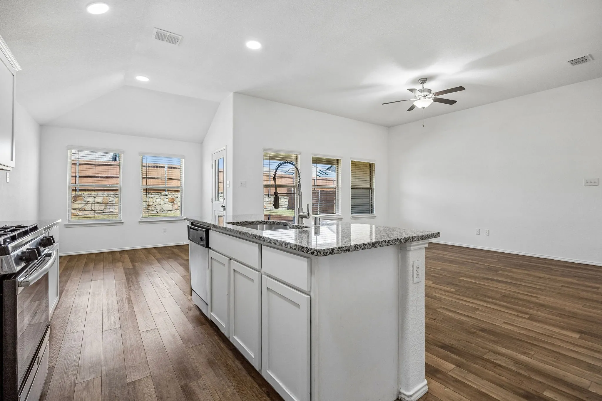 Kitchen island with granite countertop, undermount sink, and white cabinetry