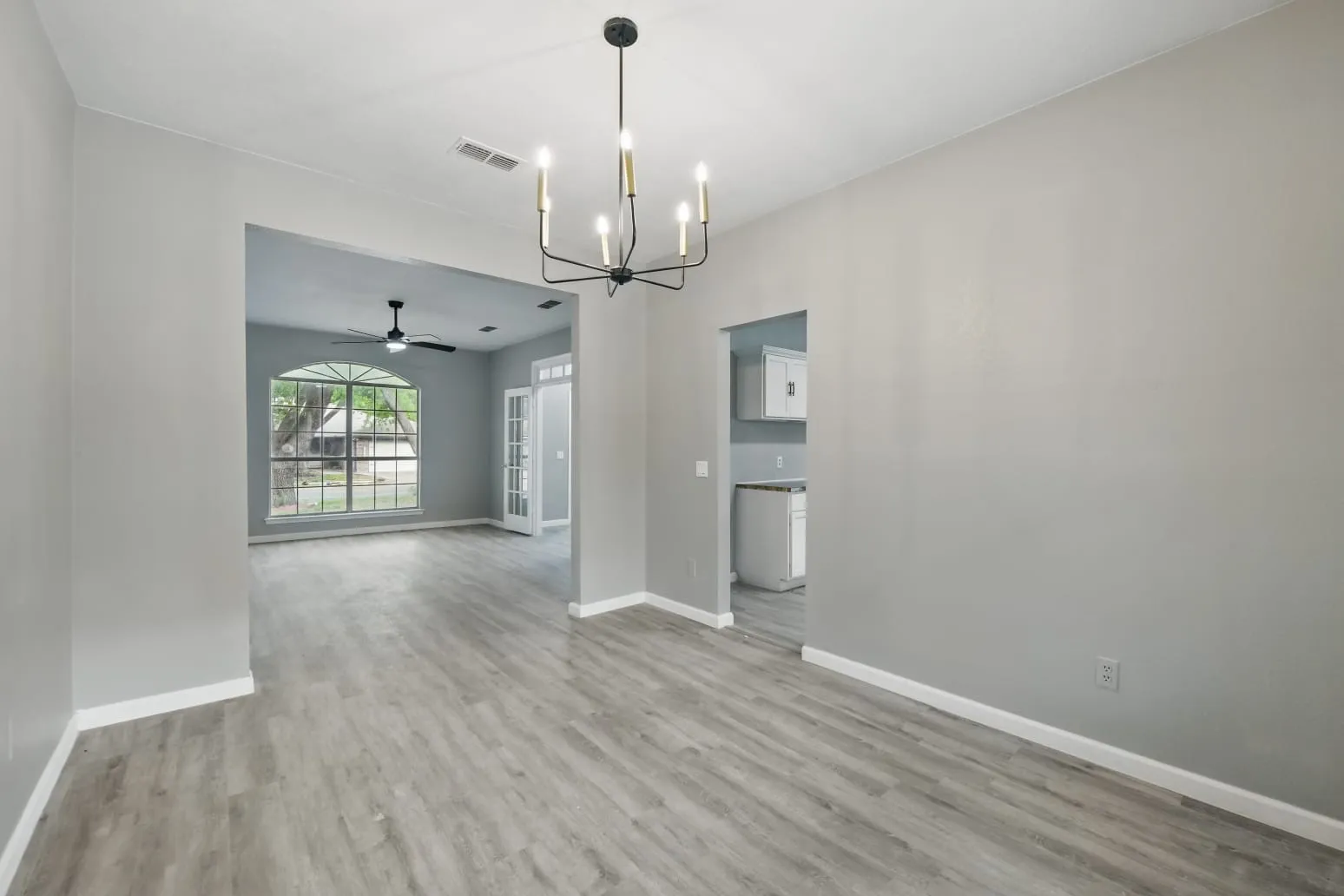 Spare room with a chandelier, wood finished floors, and ceiling fan
