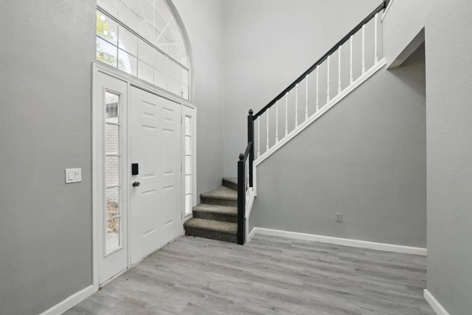 Entrance foyer featuring stairs, wood finished floors, and a towering ceiling