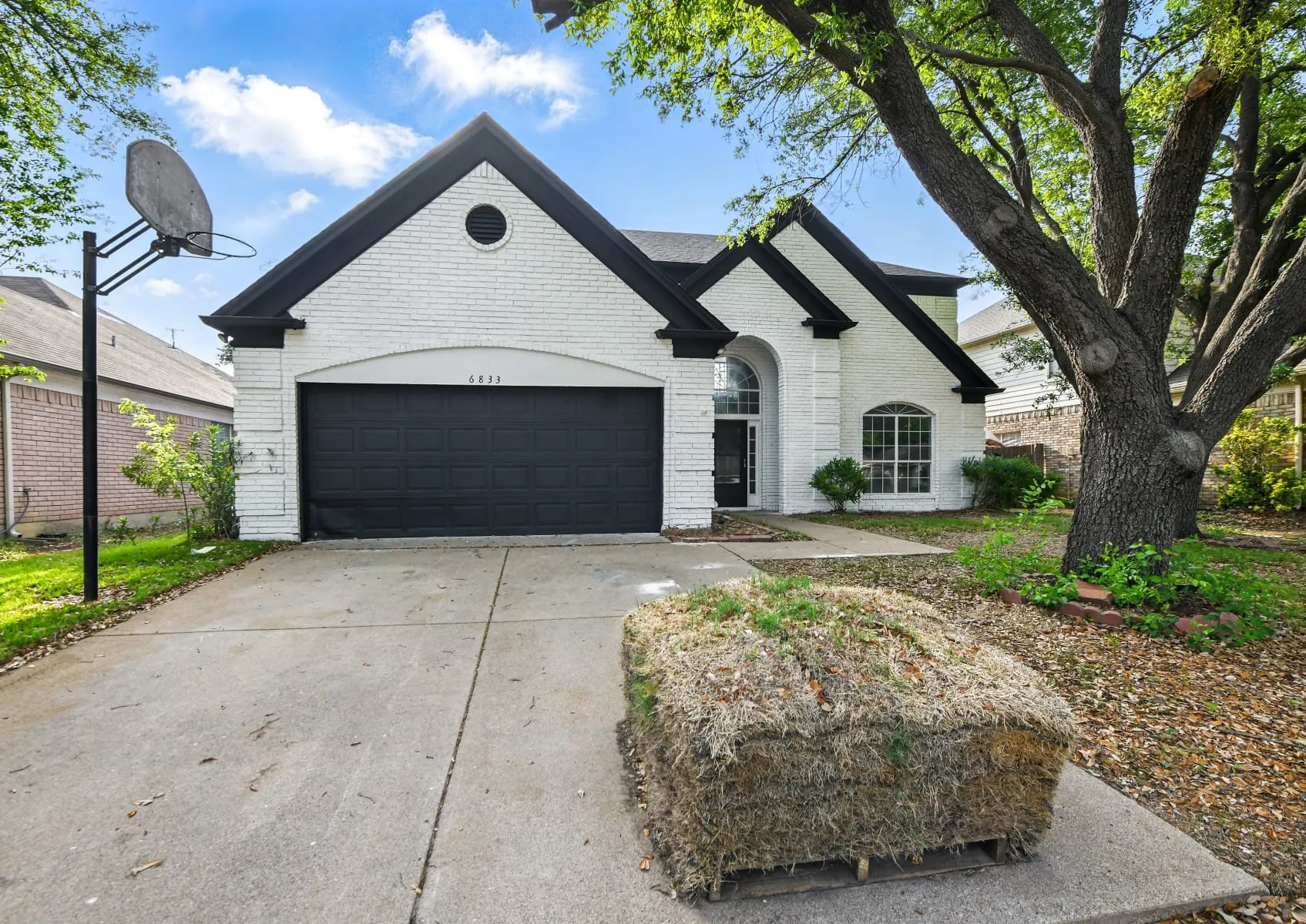 View of front of property with brick siding, an attached garage, and driveway
