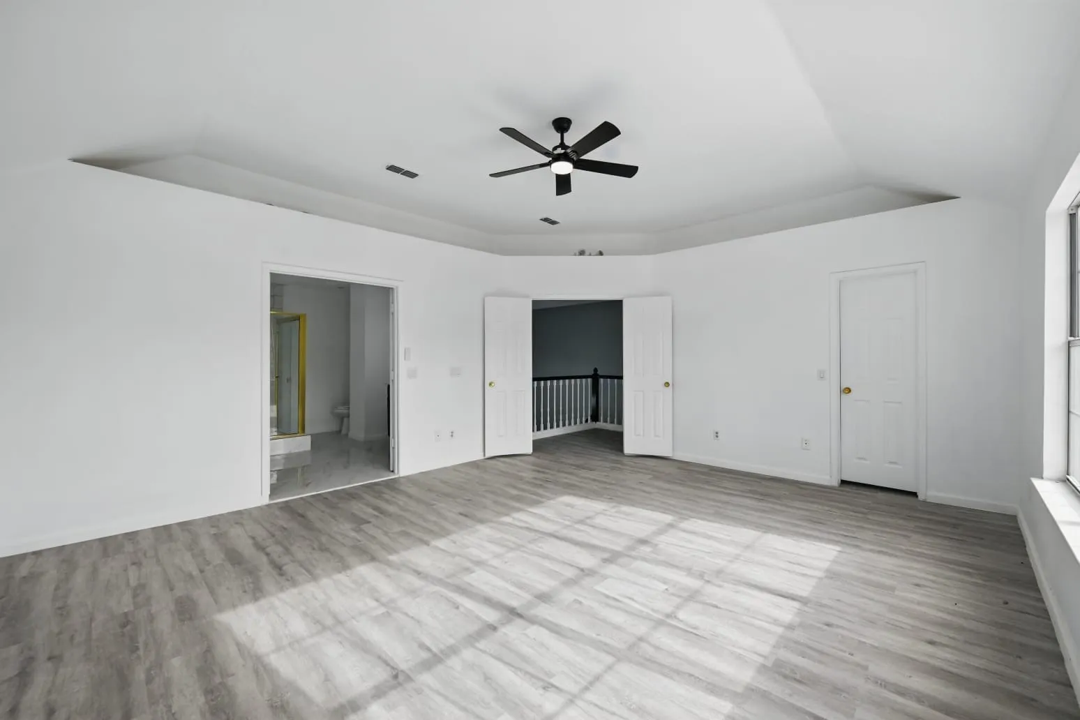 Unfurnished bedroom featuring wood finished floors, a raised ceiling, and connected bathroom