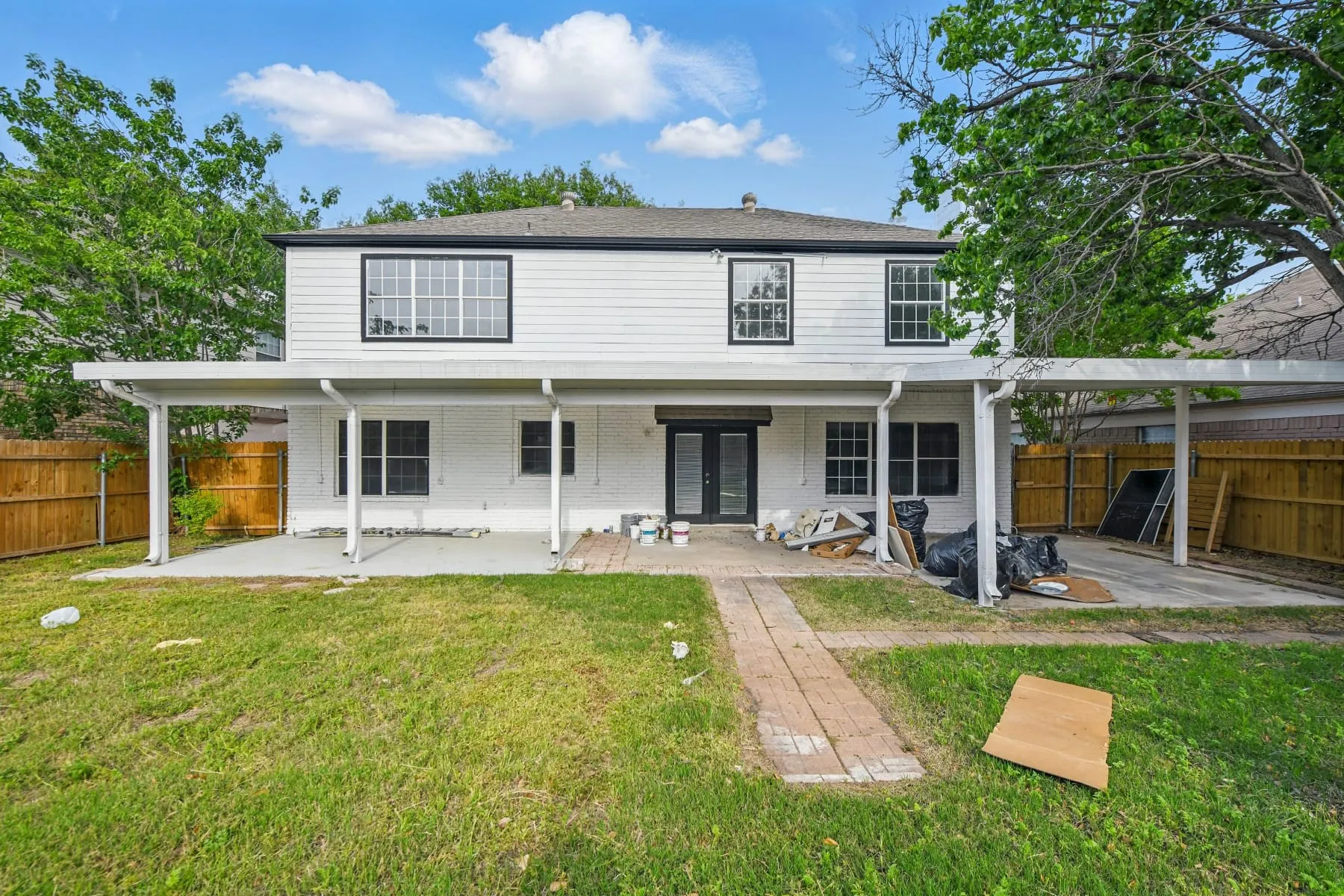 Back of property with a patio area, a fenced backyard, brick siding, and french doors