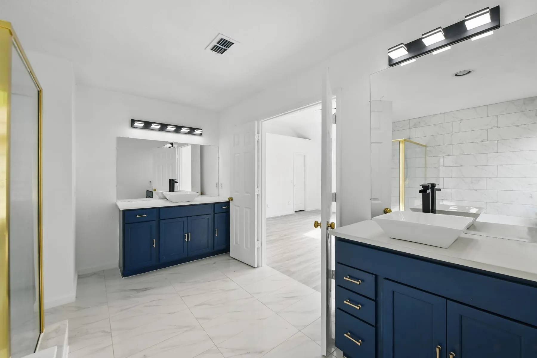 Bathroom featuring two vanities, marble finish floors, and a walk in shower
