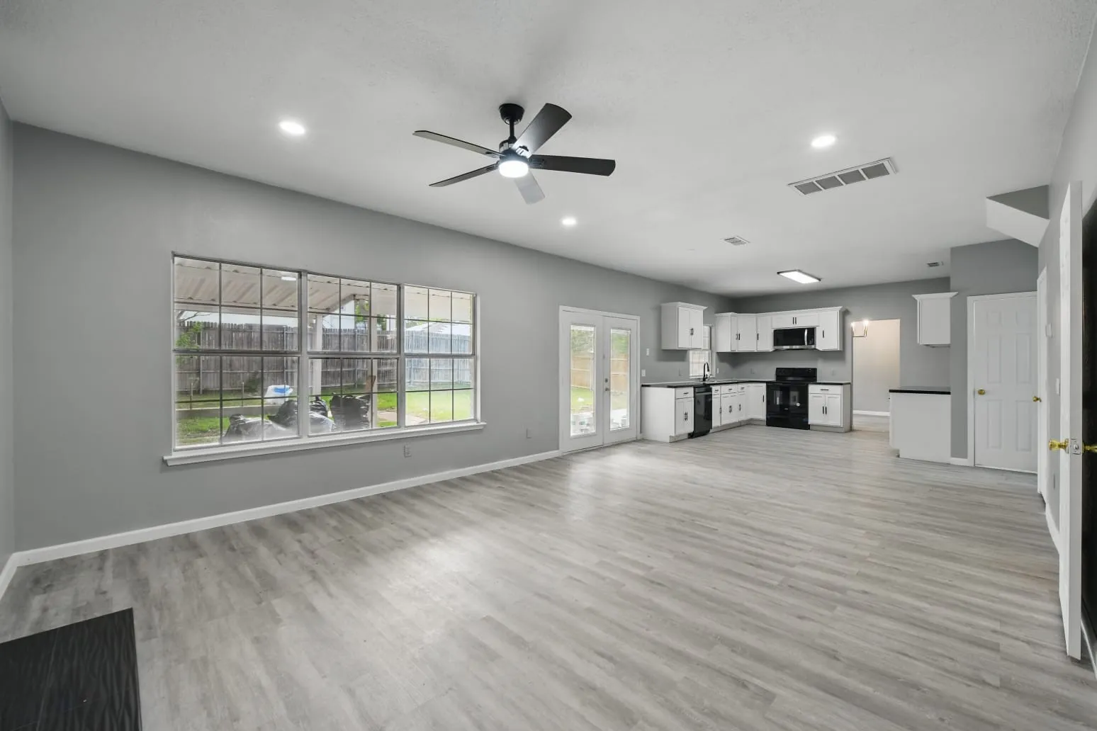 Unfurnished living room with a ceiling fan, light wood finished floors, french doors, and recessed lighting