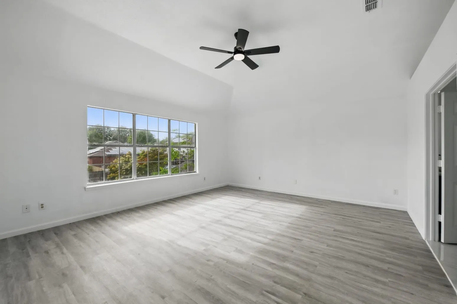 Spare room with ceiling fan, wood finished floors, and high vaulted ceiling