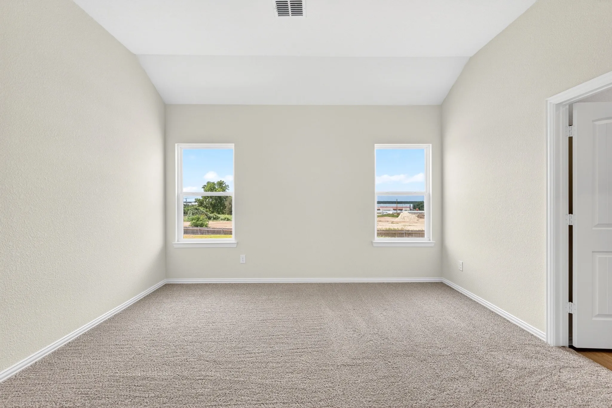 Vaulted ceiling and neutral tone walls, featuring two windows, and carpet flooring