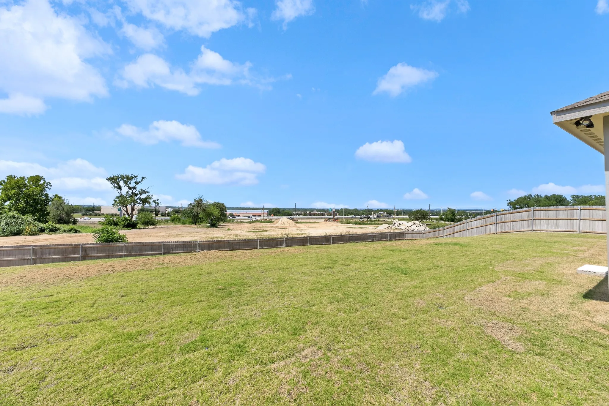 Expansive backyard featuring a manicured lawn and wood privacy fencing