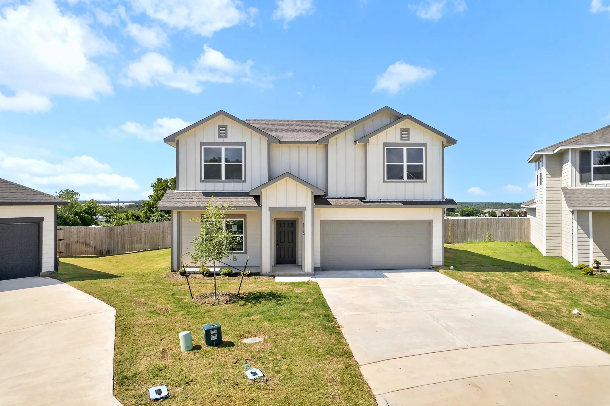 Two-story residence with a light-toned exterior, dark-toned front door, and an attached garage