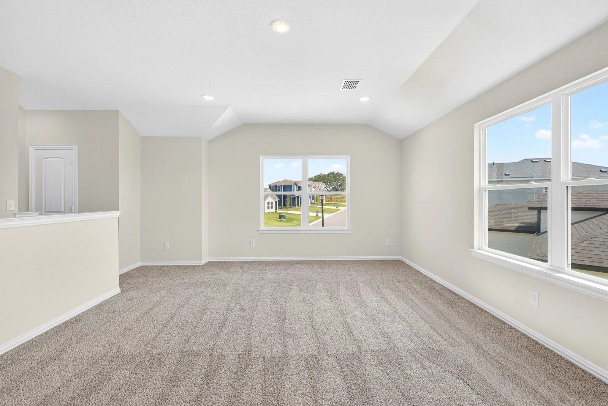 Carpeted room featuring recessed lighting, a vaulted ceiling, multiple windows, and a built-in half-wall