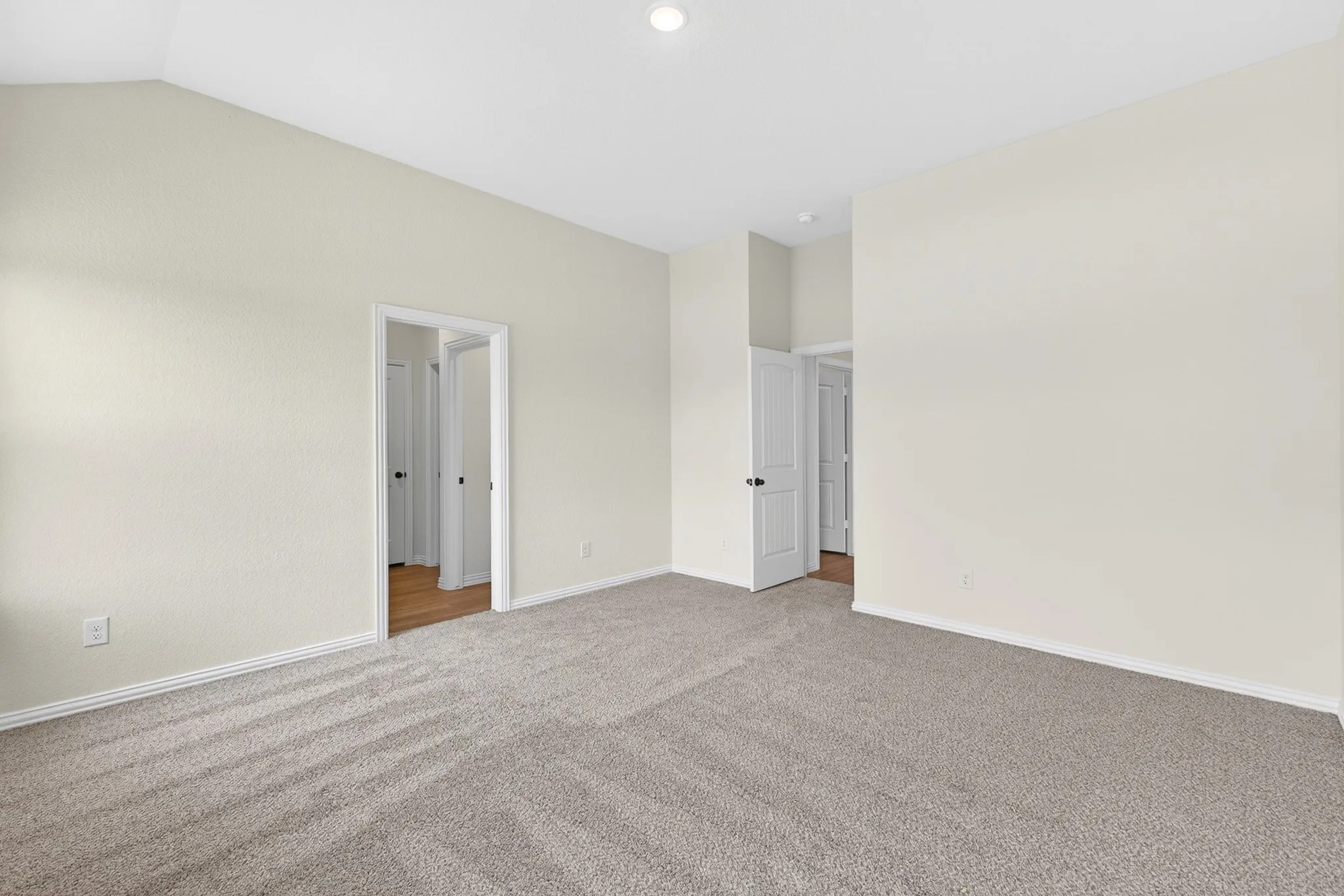 Vaulted ceiling, recessed lighting, neutral-toned walls, and carpeted flooring