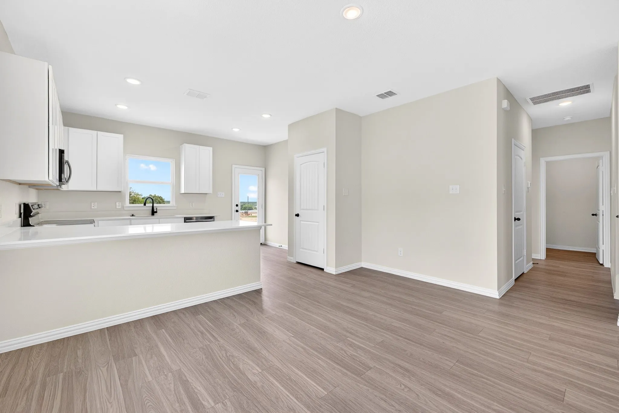 Open-concept living area with wood-finish flooring, recessed lighting, and a kitchen island featuring a breakfast bar