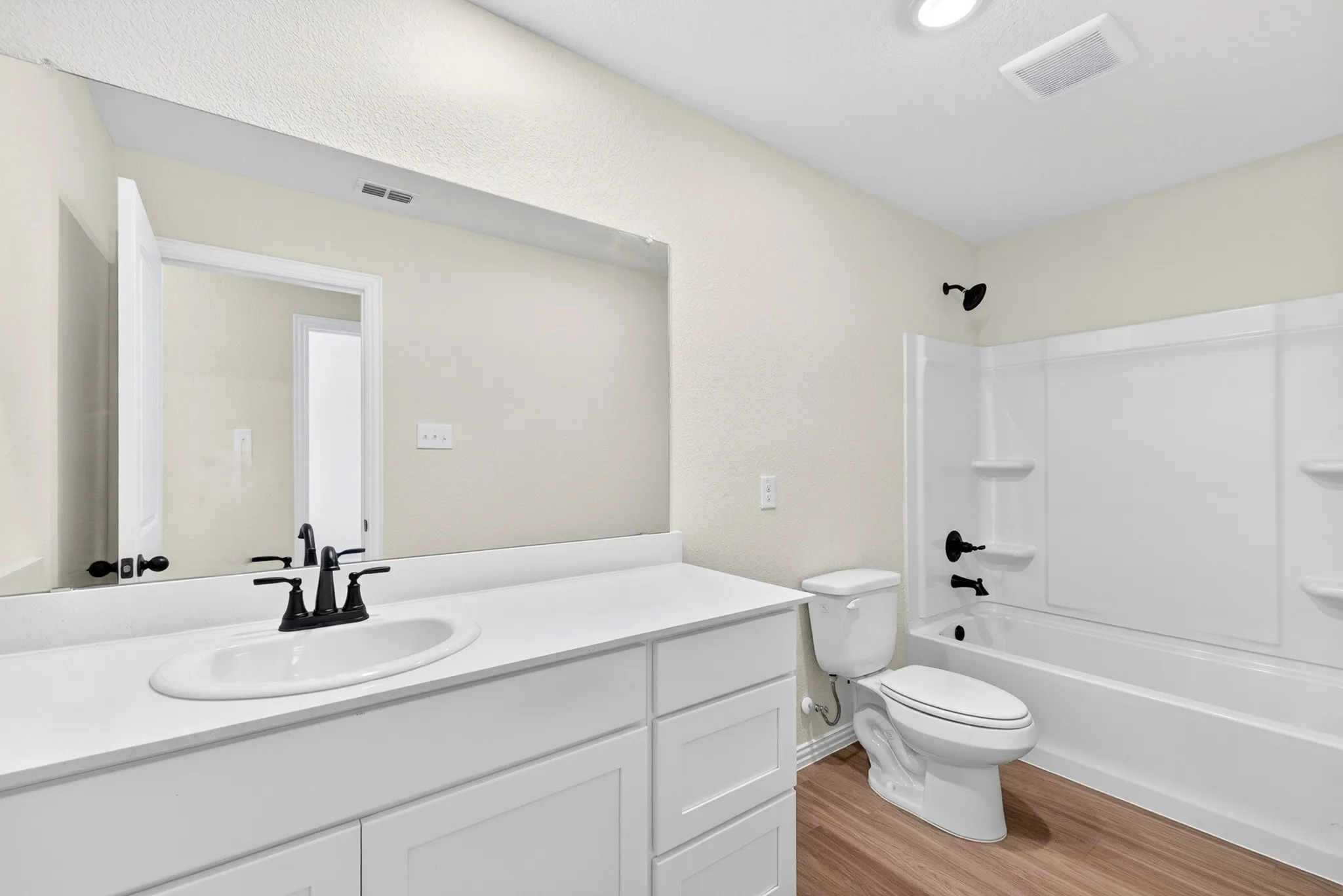 White vanity with shaker-style cabinetry, an integrated sink, and matte black fixtures
