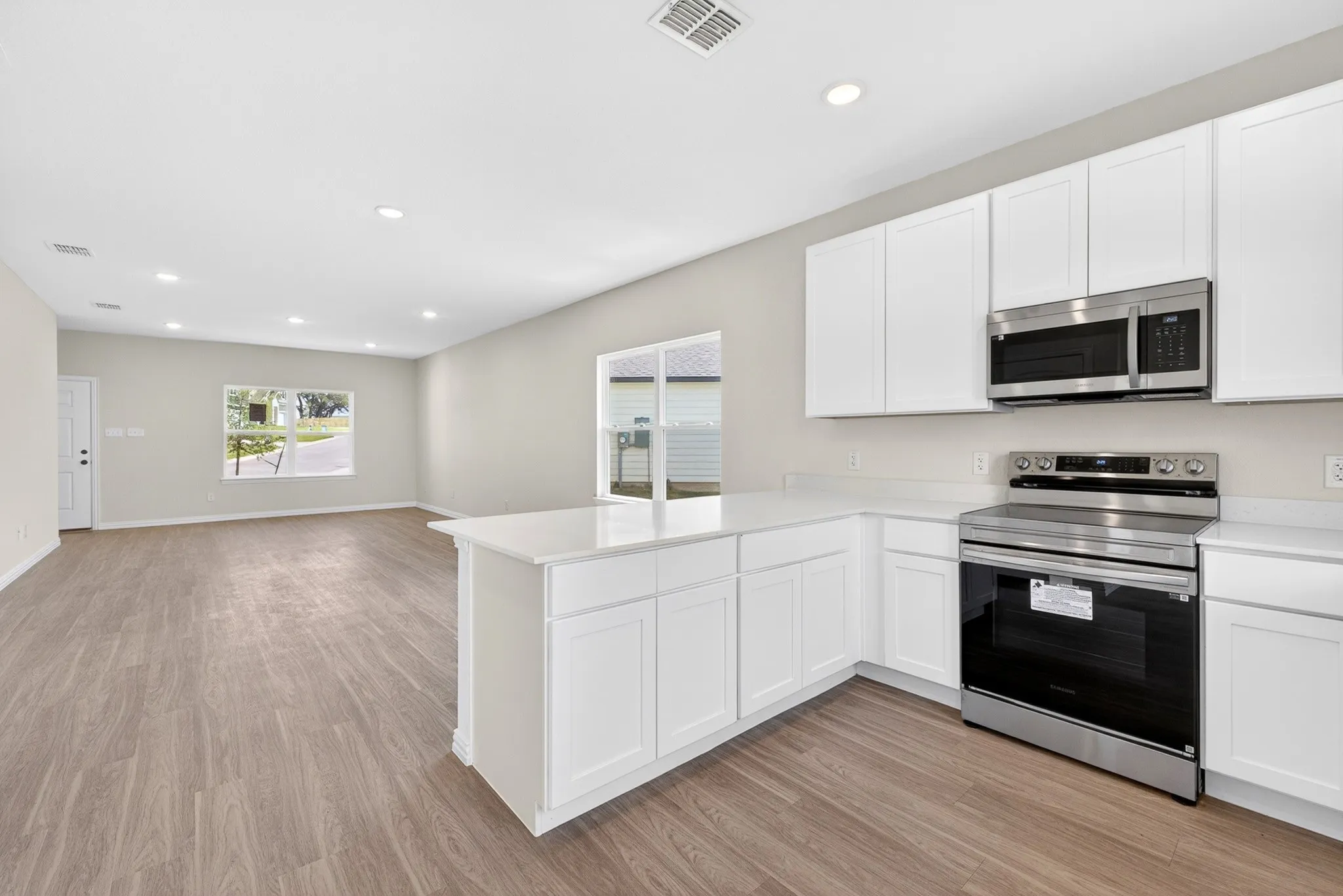Kitchen featuring white cabinetry, stainless steel appliances, a center island, and wood-finish flooring