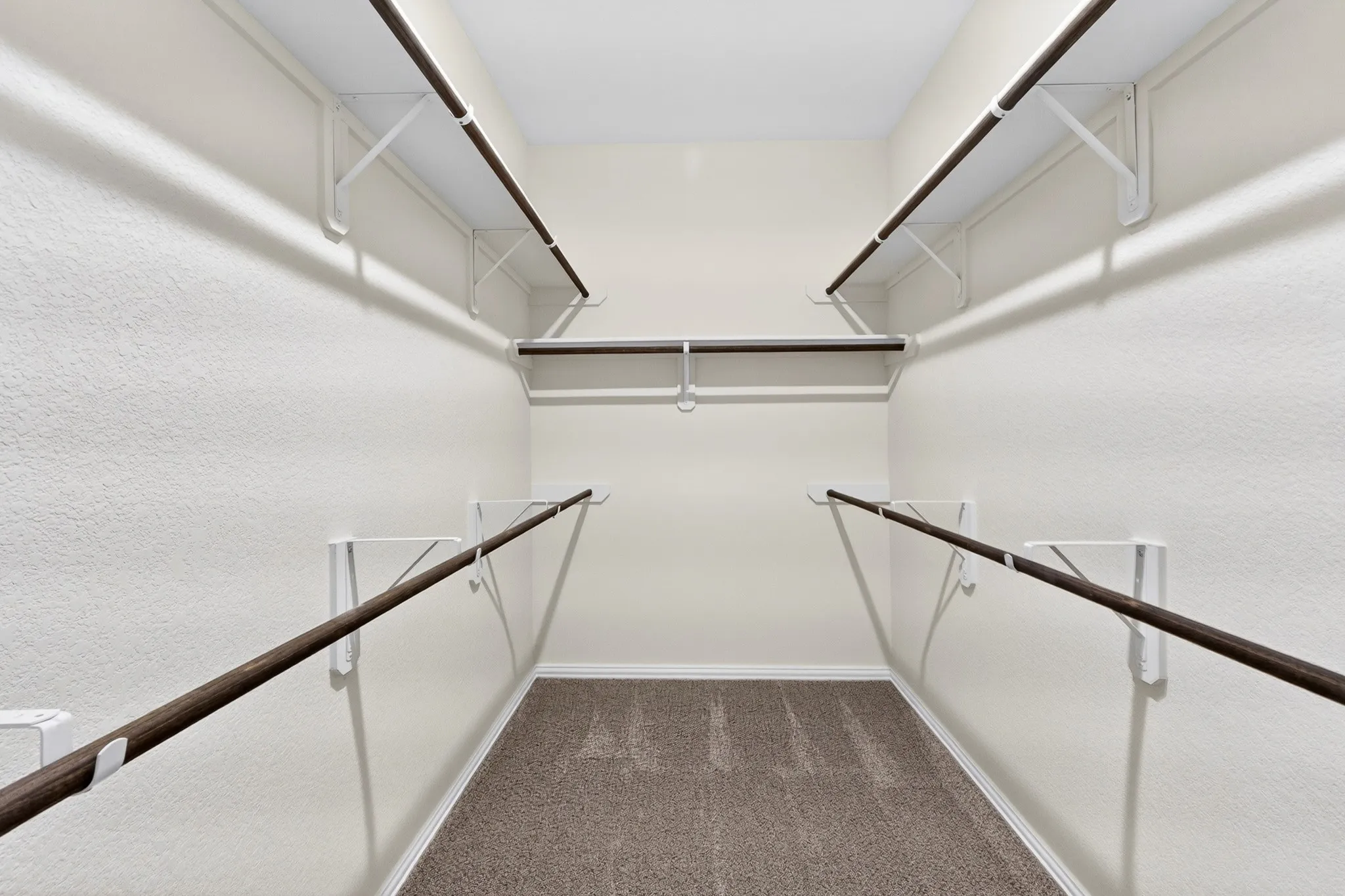 Walk-in closet with carpet flooring, white walls, and multiple levels of shelving and hanging rods