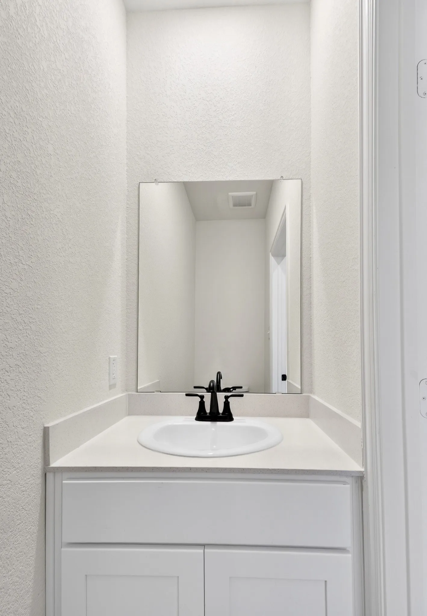 White vanity with a white countertop, undermount sink, and matte black faucet