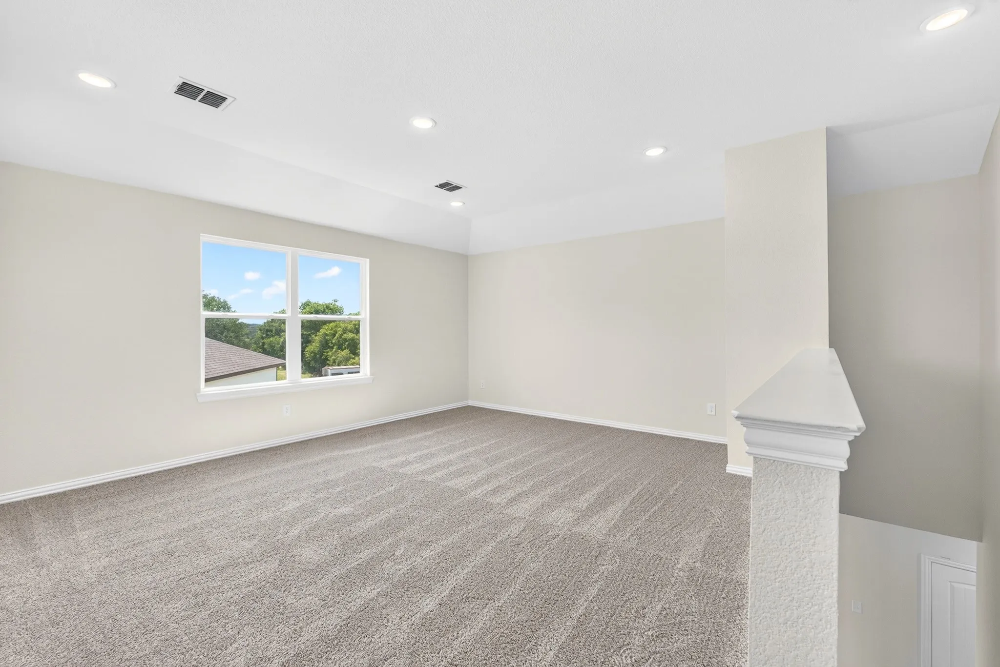Spacious room with recessed lighting, light-colored walls, carpeted flooring, and a large window