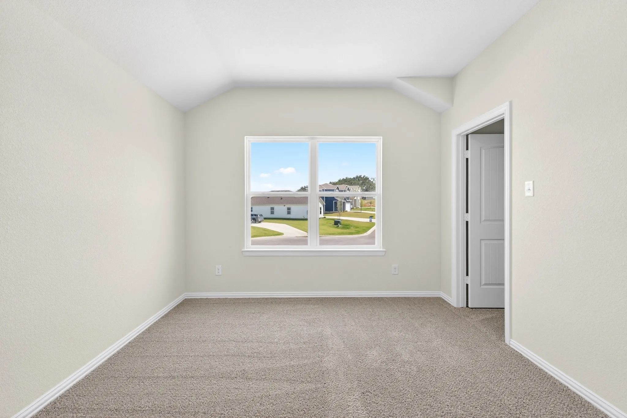 Vaulted ceiling with textured walls, carpet flooring, and a single window