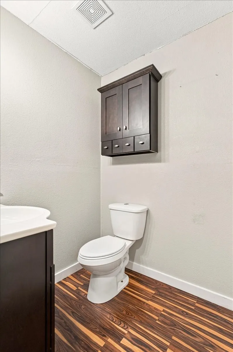 Wood-finish flooring, white walls, and a wall-mounted storage cabinet