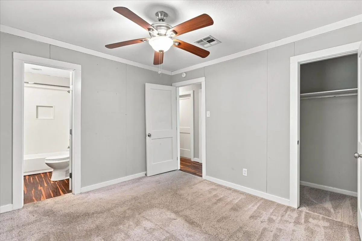 Room featuring light gray walls, carpet flooring, a ceiling fan with light fixture, and white trim