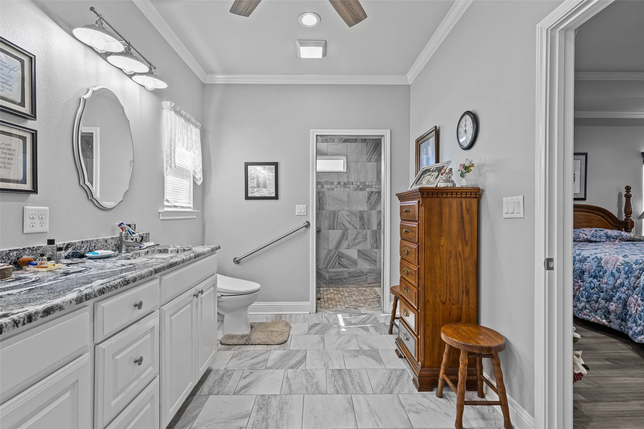 Bathroom with a tile shower, ornamental molding, toilet, and ceiling fan