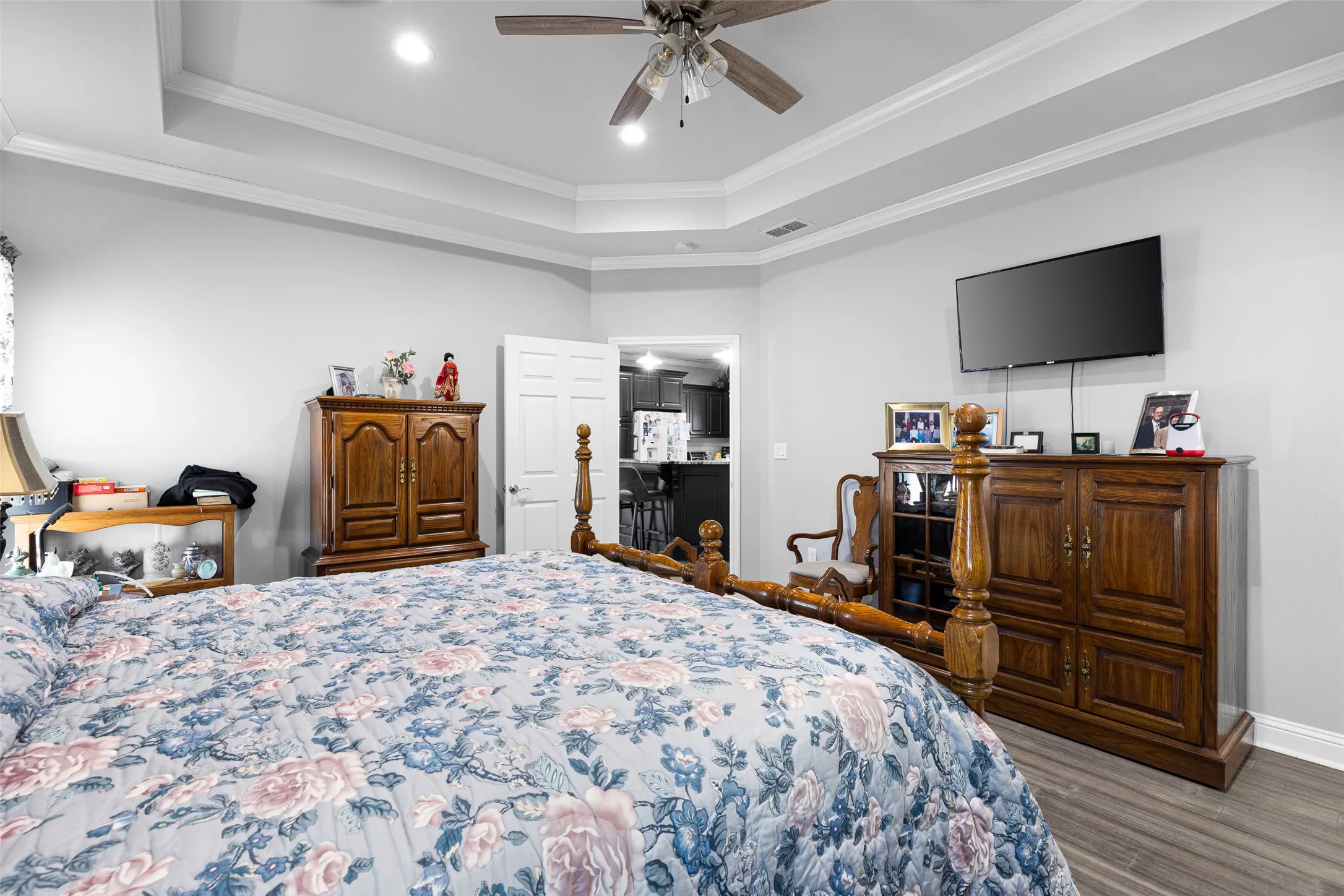Bedroom with hardwood / wood-style flooring, ornamental molding, a raised ceiling, and ceiling fan