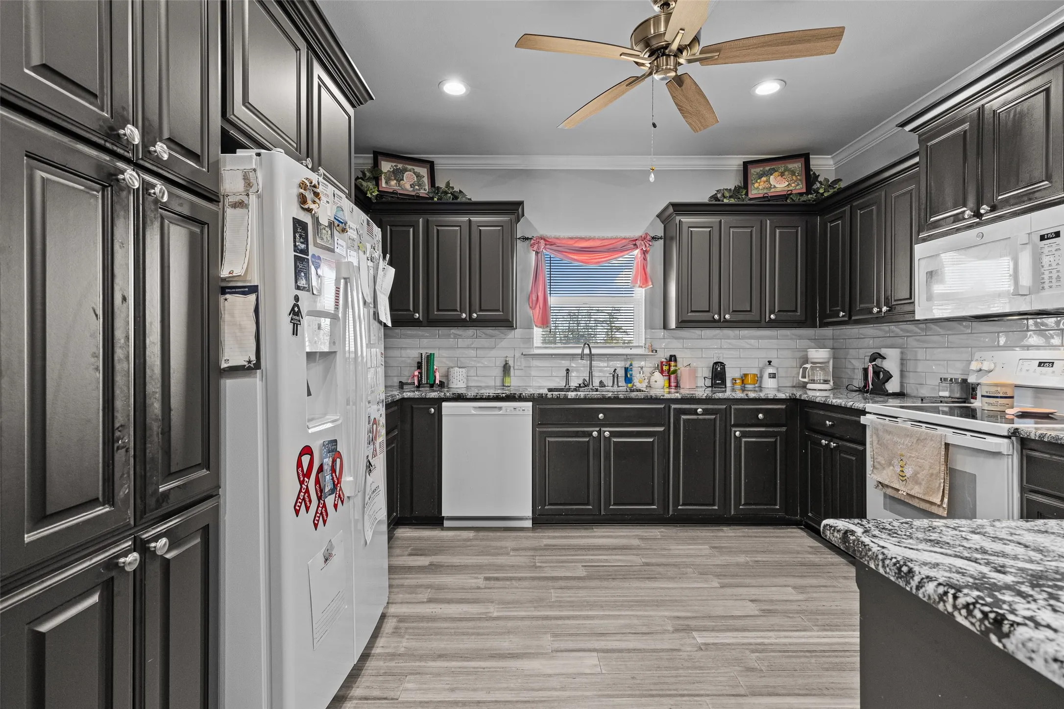 Kitchen with tasteful backsplash, sink, white appliances, and ornamental molding