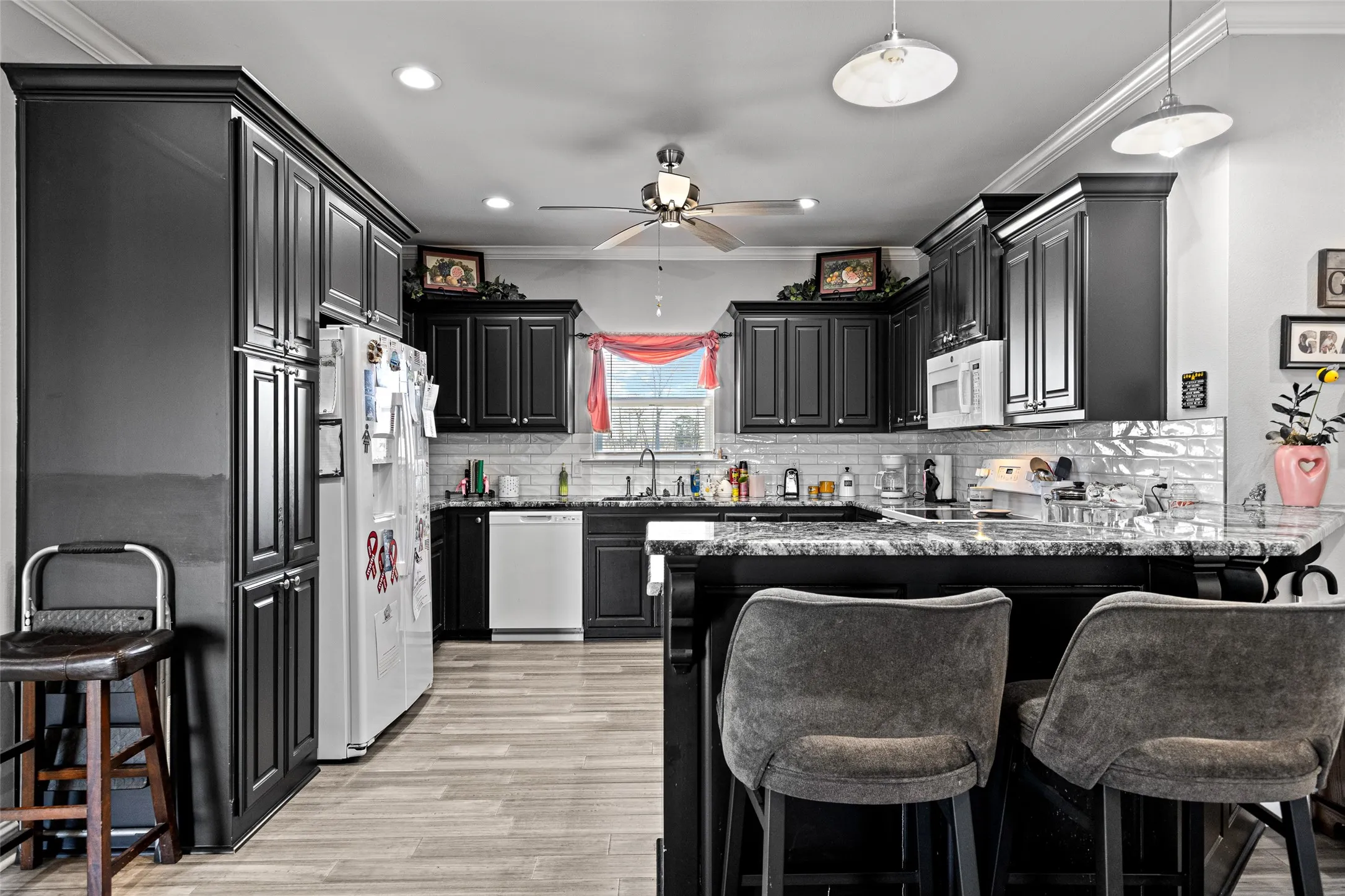Kitchen with sink, white appliances, a kitchen breakfast bar, stone countertops, and kitchen peninsula