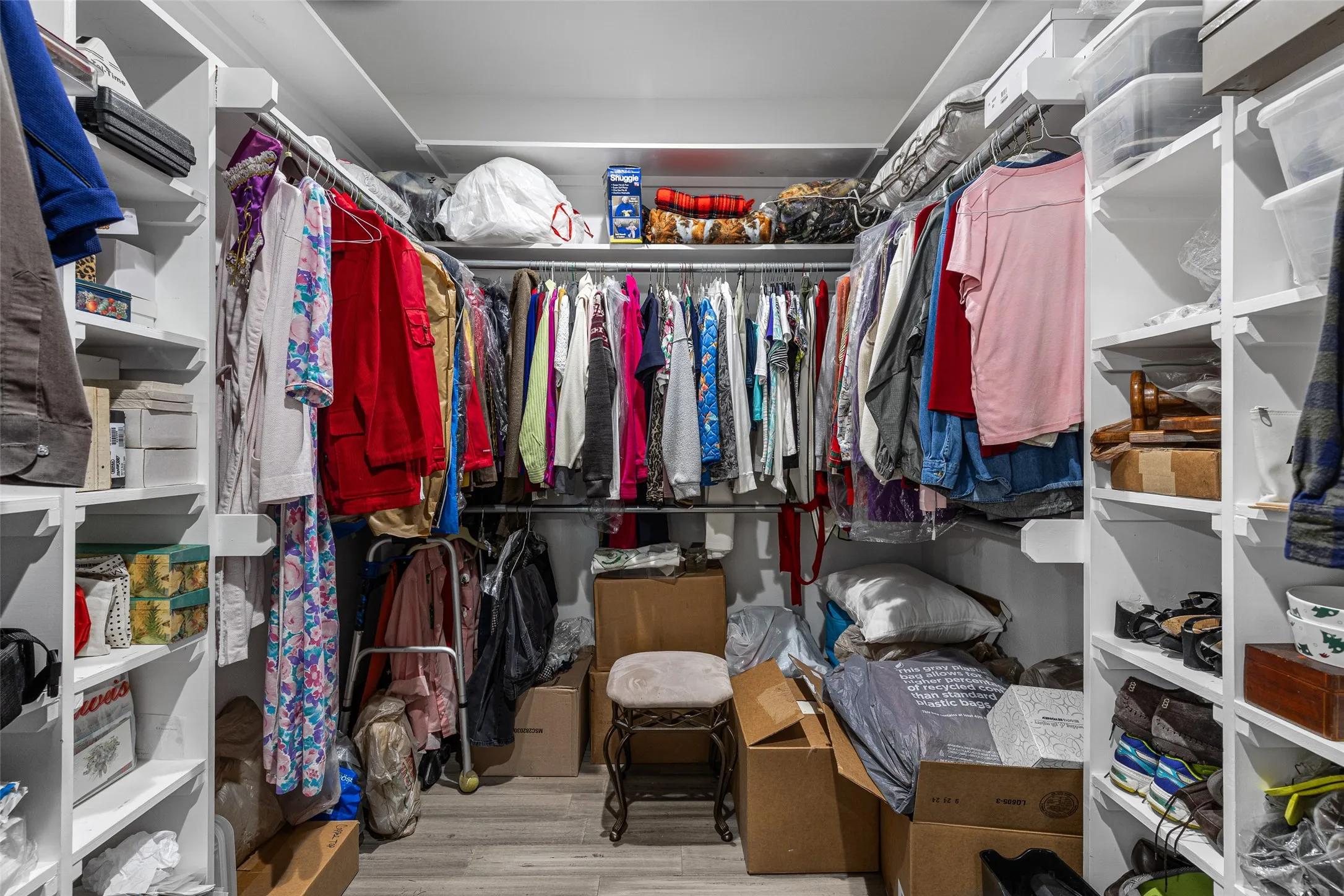 Walk in closet with light hardwood / wood-style flooring