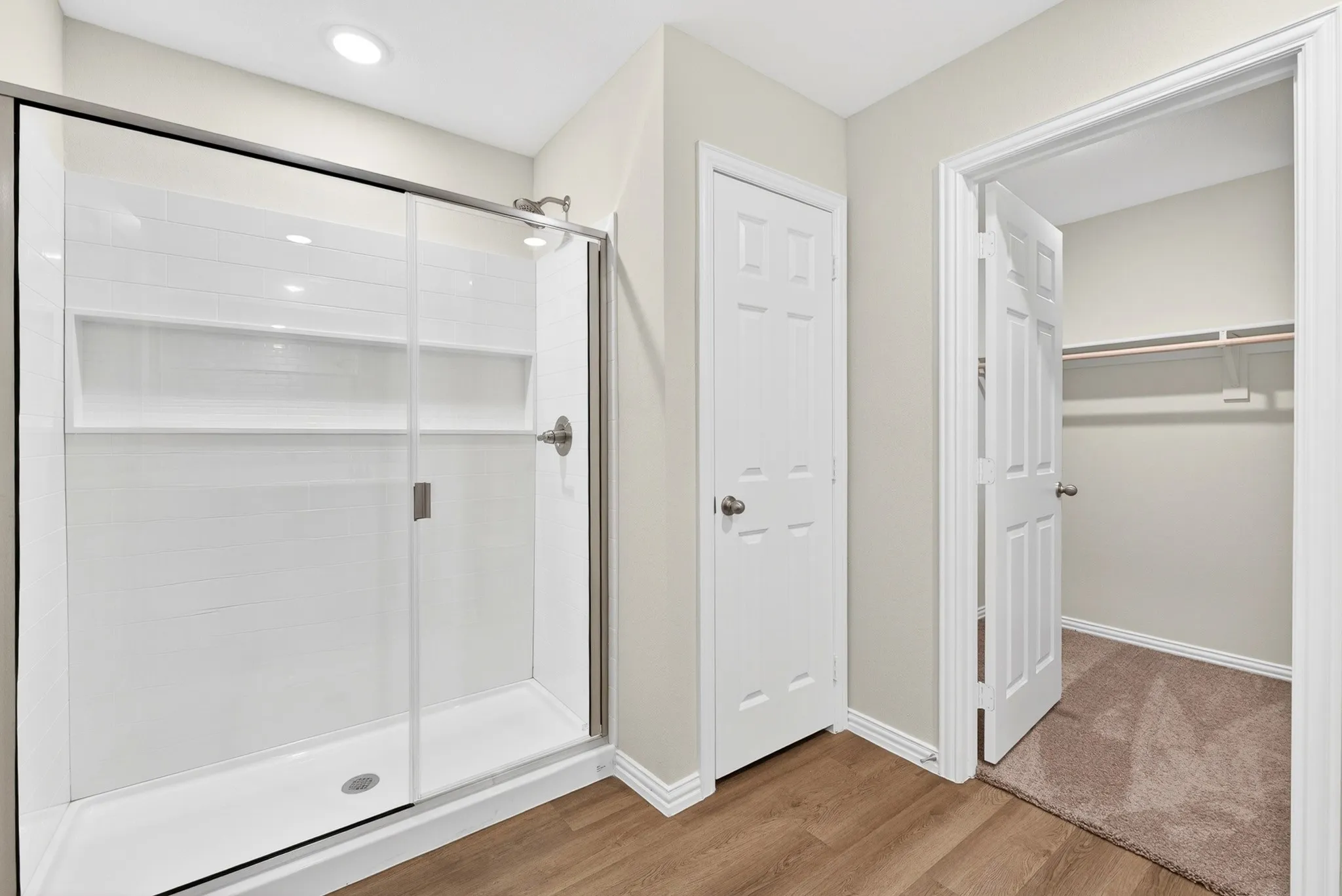 Glass-enclosed shower with white subway tile, integrated shelving, and brushed nickel fixtures