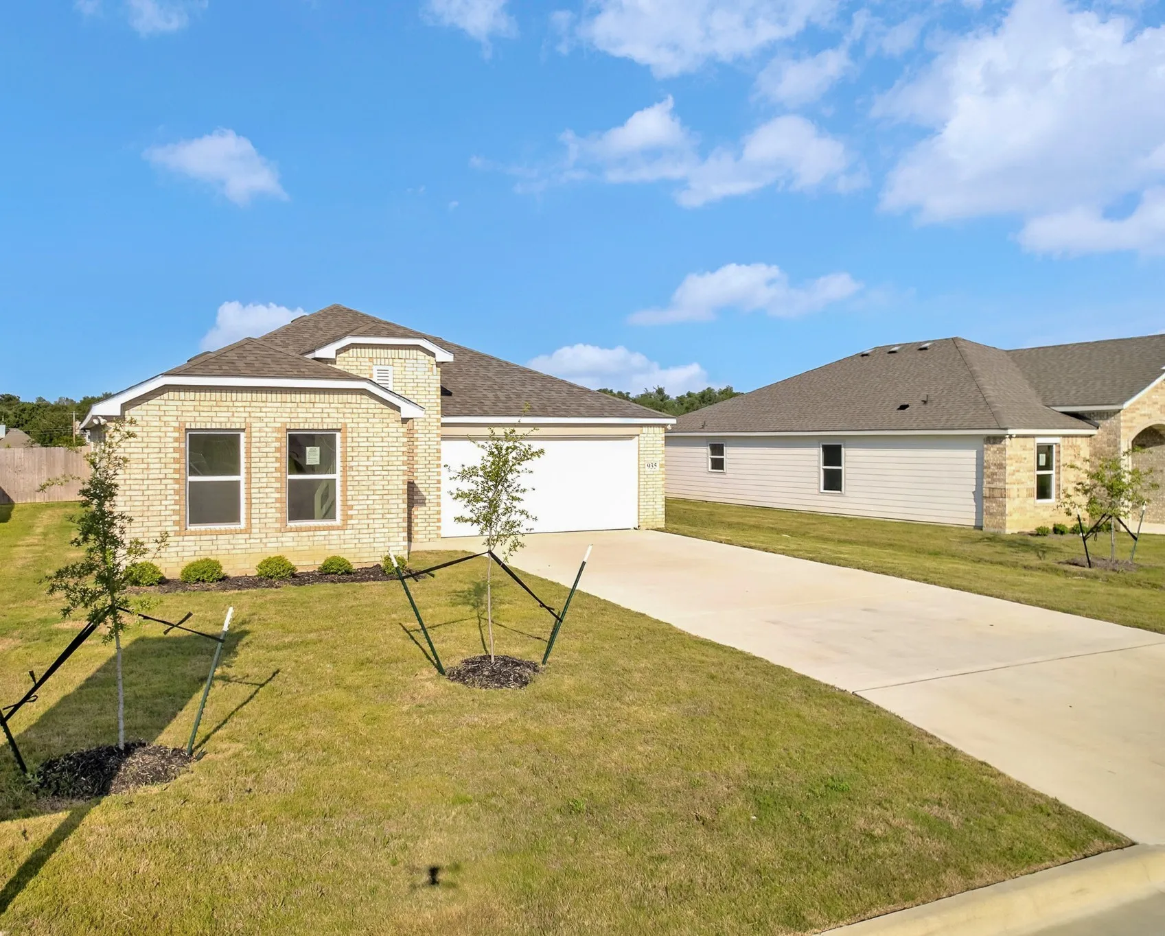 Exterior featuring light-colored brick, a two-car garage, and a concrete driveway