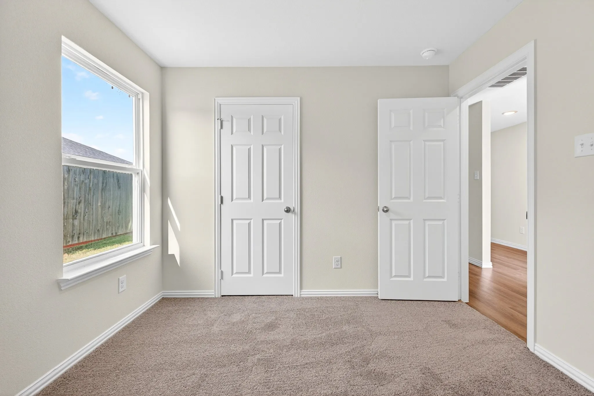 Neutral tone wall paint, recessed ceiling light, carpet flooring, a single window, and a white trim