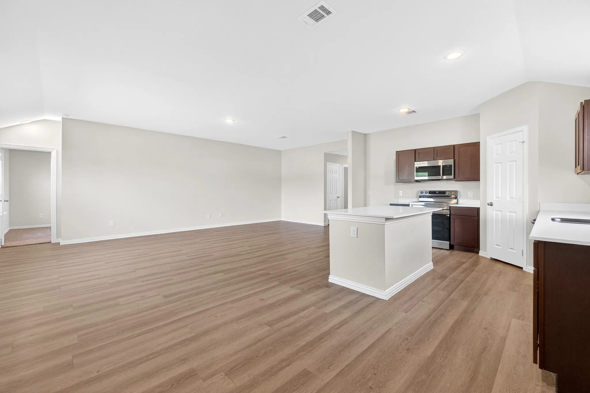 Open-concept living space featuring wood-finish flooring, recessed lighting, and a kitchen island with a white countertop