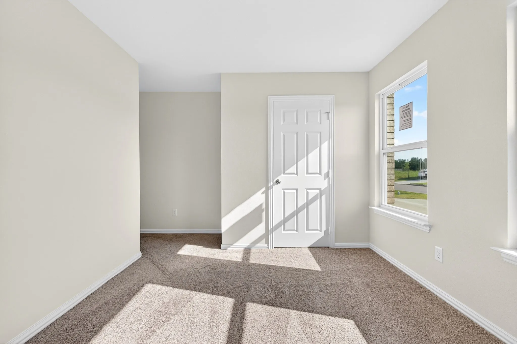 Neutral wall paint, white trim, carpet flooring, a multi-pane window, and a paneled door