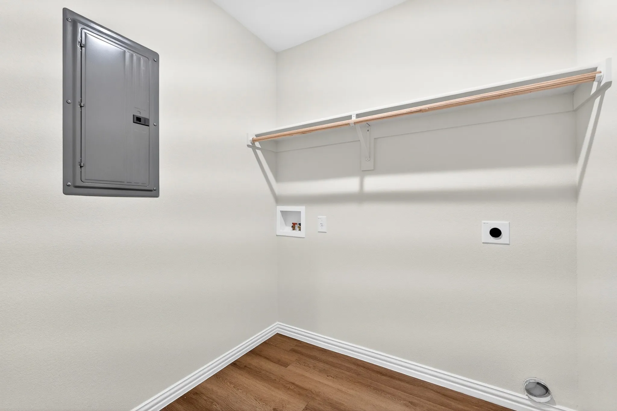 Utility room featuring white drywall construction, wood-finish flooring, and multiple built-in storage solutions including a gray metal cabinet, wire shelving with wood-tone trim, and recessed wall-mounted fixtures for organized functionality