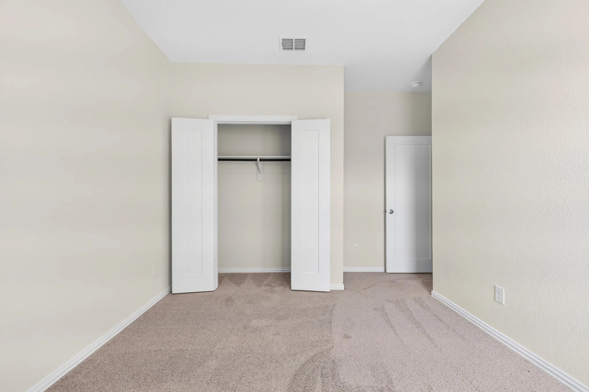 Neutral wall tones, carpet flooring, a built-in closet with bi-fold doors, and a ceiling light fixture