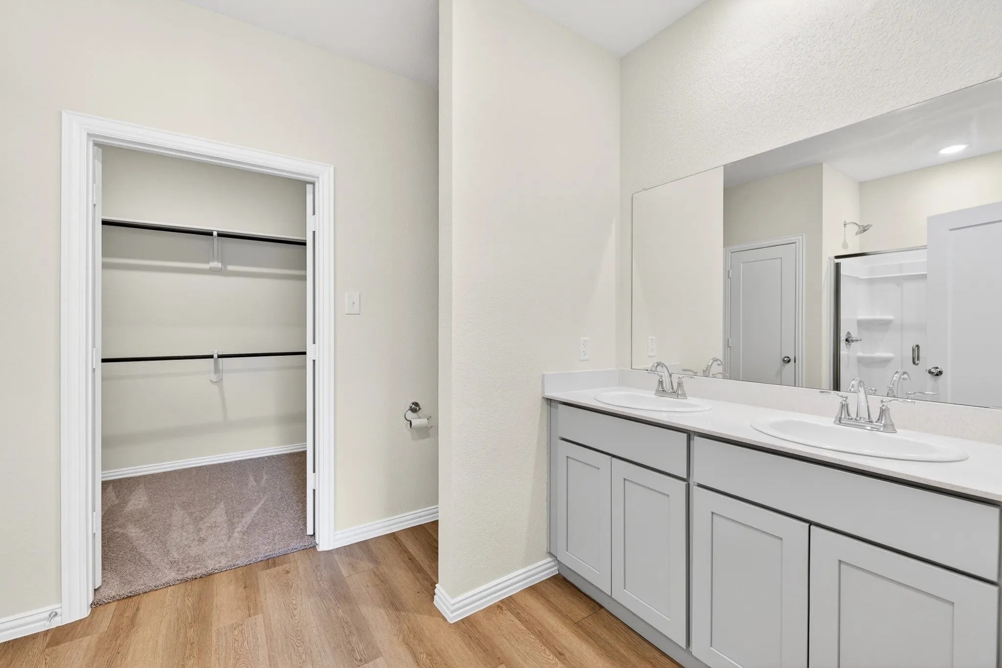Dual vanity with undermount sinks, wood-finish flooring, and a walk-in closet with built-in shelving